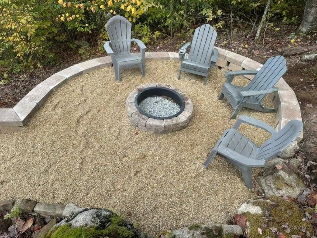 A cozy fire pit area with Adirondack chairs situated on a gravel pad, offering a perfect spot for gathering after a day outdoors. The natural setting invites guests to relax, share stories, and stargaze.