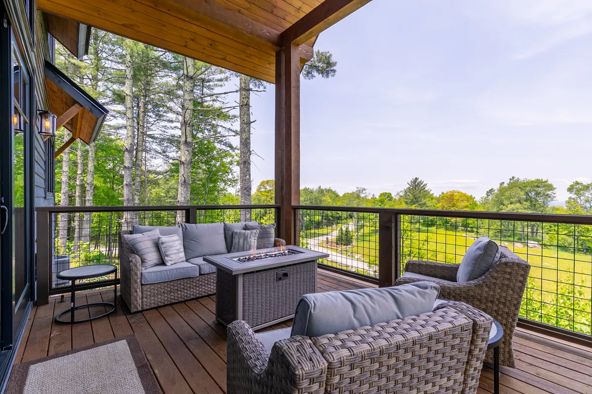 An inviting fire pit table surrounded by comfortable seating sits among green landscaping. The area is designed for relaxation and social gatherings, with the fire pit offering warmth during cool evenings.