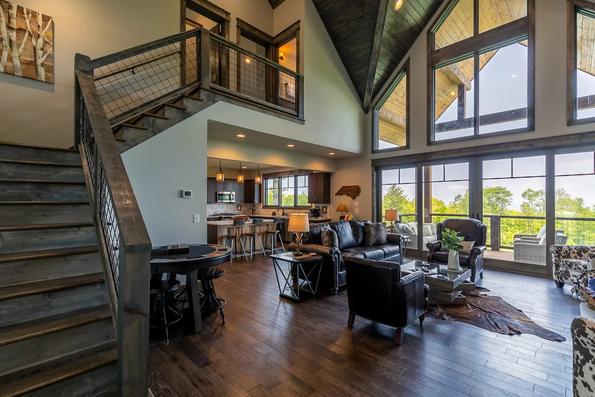 A bright, open living area with modern furniture and expansive windows that reveal beautiful natural scenery beyond. The space encourages relaxation and togetherness, with clear sightlines to the outdoors.