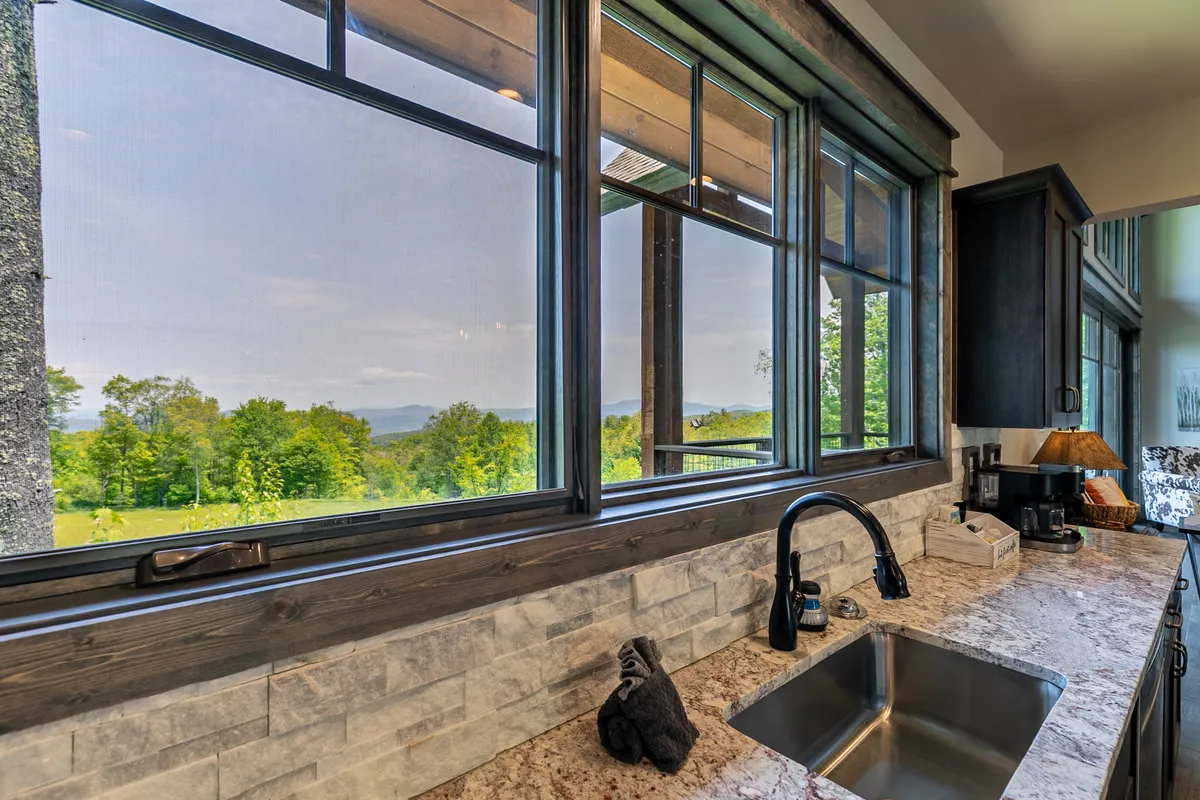 A tranquil kitchen scene with expansive windows above the sink, letting in plenty of daylight and offering a direct view of the outdoors. The clean countertops and open layout invite moments of pause to enjoy the scenery, whether starting the day or winding down after an adventure.